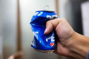 A person crushing a can of soda